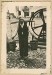 A Jewish man carries water buckets balanced on his shoulders.