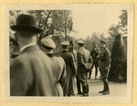German officers gather for a meeting at an unidentified locale; one takes photographs of the event.