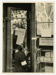A Jewish woman wearing an armband looks at a grocery shop window in the Warsaw ghetto.