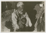 An older man and young child [probably Sephardic] sit outsie a tent.