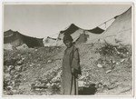 A child, (probably from a Sephardic home), stands outside a tent colony.