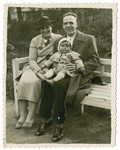 Tola and Maurice Reinberg sit on a park bench with their baby daughter Halina.