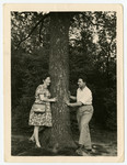 Nachman and Miriam Sadik pose on opposite sides of a tree.