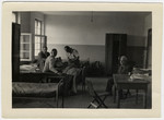 Maurice Levitt sits by a table while others gather on cots in the dormitory in Bremerhaven.
