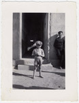 A small boy smiles as he stands outside a building at the Rivesaltes internment camp.