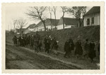A German soldiers escorts a column of people in an unidentified locale.