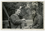 Two Jewish men play chess outside on a veranda. 

Pictured on the left is donor's uncle Pinchas Rabinowitz.