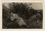 Sonia Boldo lies in a flower bed holding a kitten in prewar Nowogrodek.