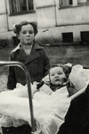 Shalom Kaplan stands next to his sister Yehudit who is in her baby carriage.