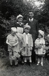Children holding flowers pose with their father and [probably mother].