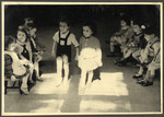 Two children walk hand-in-hand in a classroom in the Nos Petits Jewish kindergarten while other children watch on either side.