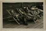 SS officer Karl Hoecker relaxes with women in lounge chairs on the deck of the retreat in Solahuette.