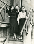 A photo of two women and one man standing on the staircase of a building.