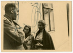 An SD officer questions two women before an unidentified exterior.