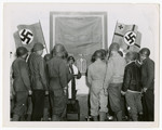 Jewish soldiers gather for a prayer service in a room still bedecked with Nazi flags.
