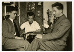 Mendel Grosman (right) sits in a parlor with two friends.
