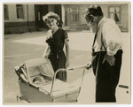 Shmuel Dawid Grosman pushes his grandson in a baby carriage while his younger daughter Ruszka looks on.