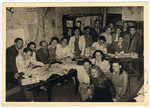 A group of Belgian Zionists gathers after the war in a room decorated with maps of Israel and filled with newspapers and books.