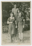 Three young women wearing armbands pose by a tree in the Bedzin ghetto.