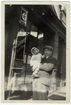 Leo Kaelberman holds his daughter Ellen outside a business in Mannheim, Germany adorned with a Nazi poster.