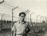 Dario Navarra poses in front of the barbed wire fence in the refugee camp in Cyprus.