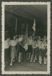 Zionist youth holding flags stand in formation in a children's home in Switzerland.