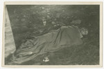 Close-up of a corpse covered with a blanket and lying on the grounds of the Woebbelin concentration camp.