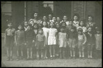 Group portrait of school children standing outside a building in an unidentified displaced persons camp.