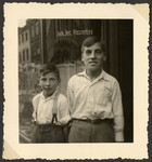 Close-up portrait of two German-Jewish brothers, Hermann (later Heinz) and Willi Rosenfeld, standing in front of their father's bakery at Trier, Neustr.