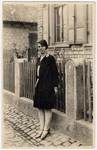 Portrait of Paula Kahn, a German-Jewish woman standing outside a building next to a fence.