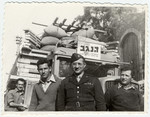 UNNRA director Mordecai Schwartz poses in front of a truck loaded with bundles and lumber to resettle Jewish displaced persons in southern Israel.
