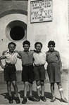Four boys pose together in front of a Hebrew/English sign at the Kloster Indersdorf children's home.