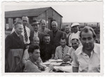 Jewish men gather around an outdoor table in the Kitchener refugee camp.