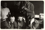 German POWs discuss amongst themselves while a Polish priest lights Julien Bryan's cigarette in the background.