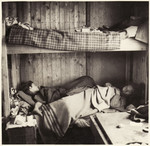 A woman and young boy lie on the bottom bunk inside a barrack at the Bergen-Belsen concentration camp.