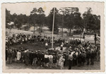 Tarbut School students in the Foehrenwald D.P. camp gather in a circle around a flag pole, celebrating the new year.