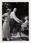 Max Weilheimer takes his son Richard for a ride on his bicycle while his wife Lilly looks on.