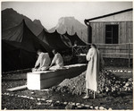 Survivors dressed in medical gowns use the latrines outside the Red Cross tent.