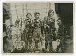 Captured female guards stand behind a barbed wire fence in the Bergen-Belsen concentration camp.