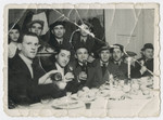 A group of men and women gather for a festive meal in the Bergen-Belsen displaced persons camp.