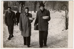 A man and woman walk through the Gabersee displaced persons camp carrying cakes.