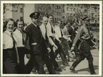 Young men and women wearing white shirts and ties march in a Nazi parade in Frankfurt.
