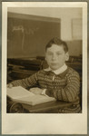 School portrait of Paul Ehrenfeld sitting at his desk reading a book.