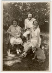 Three Austrian-Jewish sisters sit in a garden with their dog.