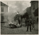 Propaganda photo showing a German soldier guarding a bonfire of burning mattresses.