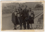 A group of teenagers hold lunch pails in case there will be a distribution of soup while standing in on Marynarska street in the Lodz ghetto.