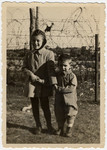 Two children pose in front of a barbed wire fence in the Ziegenhain DP camp.
