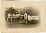 Group portrait of members of Gordonia Zionist Youth movement standing next to a flag pole in the Cyprus internment camp.