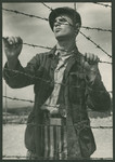 A survivor stands next to the barbed wire fence of the Buchenwald concentration camp following liberation.