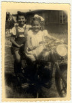 Two young girls pose on a motorcycle in the Landsberg displaced person's camp.
